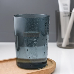 Gobelet à dents gris foncé minimaliste avec gouttes d'eau sur un plateau en bois