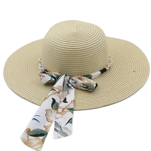 Detail of beige straw sun hat with floral chiffon ribbon and white pearl trim decoration