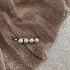 Detail of a vintage golden hair clip with four elegant white round pearls