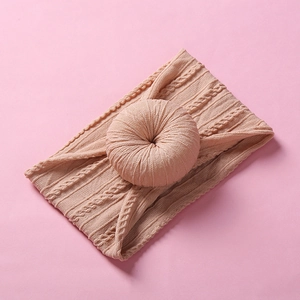 Close-up of pink soft nylon baby headband with a knitted donut bow on a matching background