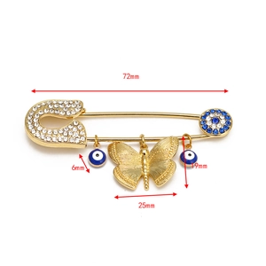 Detail of evil eye safety pin brooch with gold butterfly pendant and sparkling rhinestones
