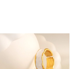 Detail of adjustable gold ring with white enamel drip and elegant irregular texture
