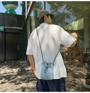 Close-up of light blue drawstring crossbody bag worn by a model in outdoor setting