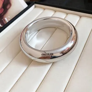 Polished silver wide open bangle minimalist chunky metal bracelet on white jewelry box