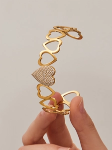 Detail of gold-plated hollow heart-shaped open bangle with sparkling pavé-set stones