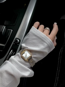 Close-up of luxury rectangular gold-tone watch with full crystal pavé on wrist