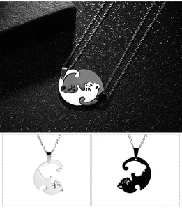 Detail view of interlocking black and silver cat heart pendants on stainless steel chains