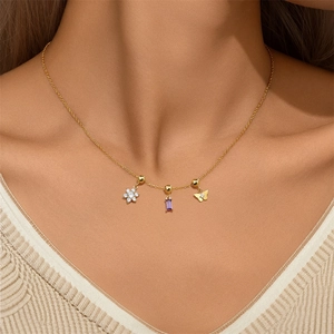 Close-up of gold chain necklace featuring purple zircon, flower, and butterfly charms