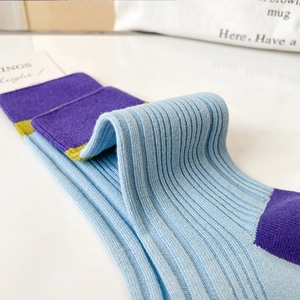 Detail of ribbed knit cotton socks in light blue with purple and yellow color blocking