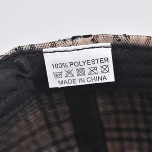 Detailed macro view of the 100% polyester washing label inside the brown plaid baseball cap
