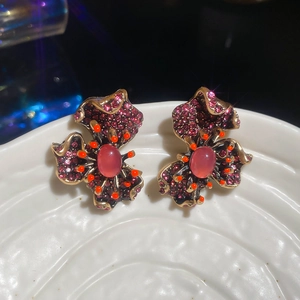 Vue macro de boucles d'oreilles vintage avec strass magenta et détails dorés raffinés