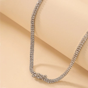 Close-up of double-row tennis necklace with sparkling diamonds on a beige display stand