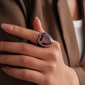 Gros plan d'une bague de luxe en zircon violet en forme de cœur sur une main