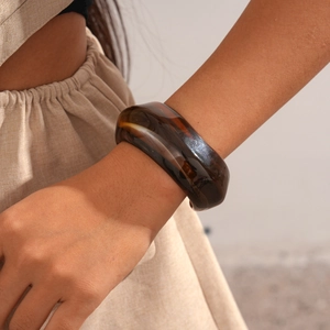 Detail shot of a wide amber resin bangle with semi-transparent texture and internal swirls