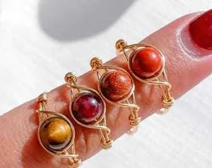 Detail of four handmade wire-wrapped gemstone rings with tiger eye and quartz beads