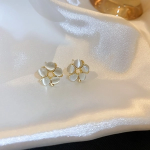 Detailed view of petal-shaped opal earrings on premium white silk background