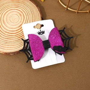 Detail of purple glitter Halloween bow hair clip with spider web on display card