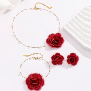 Detail of red fabric rose jewelry set with gold chains and white pearls on white stand