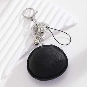 Detail of black leather round evil eye keychain with silver bells and metallic ring hooks