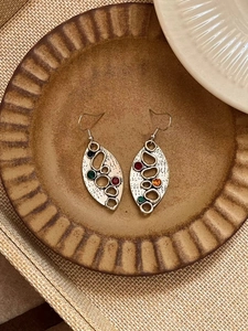 Détail macro de boucles d'oreilles ovales vintage en argent avec strass colorés