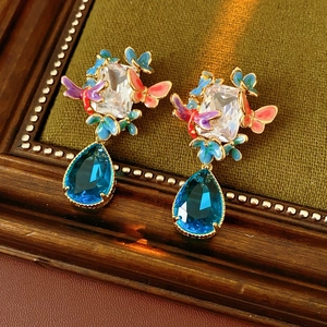 Close-up of vintage gold earrings with zircon butterflies and blue teardrop stones