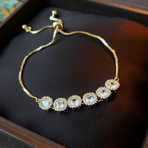 Detail of adjustable gold bracelet with square cubic zirconia in a dark velvet jewelry box