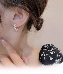 Close-up of gold woven hoop earrings with white pearls worn by a female model