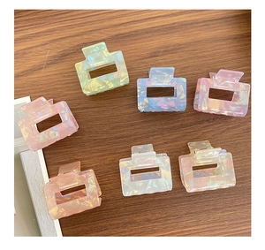 Detail of colorful iridescent square hair claws in pastel pink, blue, and green tones