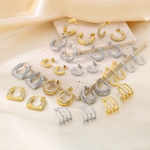 Detailed close-up of C-shaped 18K gold and silver geometric earrings with pavé crystals