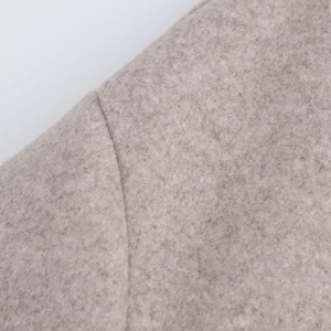 Close-up of beige wool fabric on shoulder showing premium texture and stitching detail