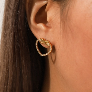 Close-up of gold heart knot earrings with sparkling rhinestones worn on a model ear