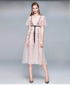 Détail d'une robe en tulle rose avec broderie florale colorée et fine ceinture noire