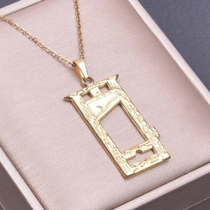 Macro shot of gold guillotine pendant on cross chain necklace in a pink jewelry box