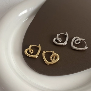 Minimalist twisted hollow heart earrings in gold and silver finish on leather display