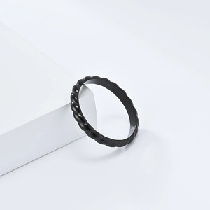 Minimalist black twisted rope ring in polished stainless steel on a white geometric base