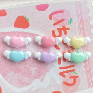 Mini resin heart wing charms in pink blue yellow and green on strawberry background