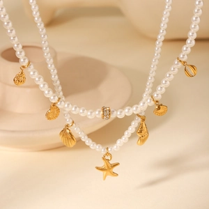 Detail of double-layer gold necklace featuring pearls, sea shells, and starfish charm