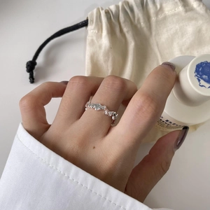 Close-up of irregular wavy S925 sterling silver ring worn on model hand in minimalist setting