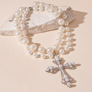 Close-up of double-layer pearl necklace featuring a vintage silver cross pendant