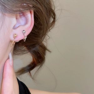 Close-up of minimalist geometric sphere clip-on earrings in gold and silver finishes