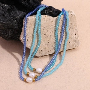 Detailed shot of three blue crystal bead necklaces with white freshwater pearls and gold beads