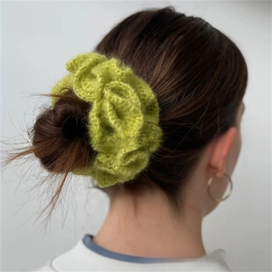Detail view of grass green hand-crocheted ruffled hair tie on a bun hairstyle