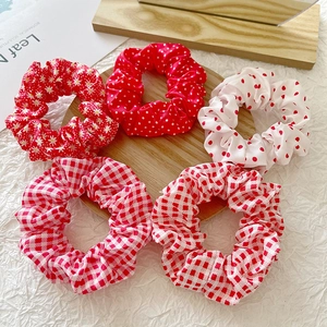 Detailed set of 5 red and white floral, polka dot, and plaid hair scrunchies on a tray