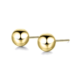 Macro shot of polished gold spherical stud earrings with a glossy mirror finish surface