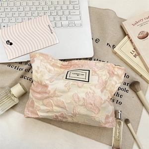 Detailed close-up of woven jacquard makeup bag with pink floral patterns and fabric label