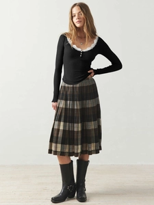 Detail des schwarzen Langarmshirts mit Spitze und braunem karierten Plissee-Rock