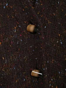 Detail of tweed knit fabric in dark brown with colorful fibers and amber gradient buttons