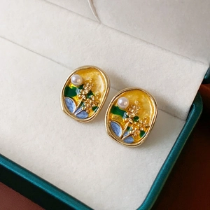 Gros plan détaillé de boucles d'oreilles émaillées fleurs ovales avec perle et cadre doré chic