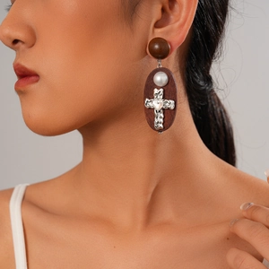 Retro cross earrings with wood plaque and pearl accents on a model's side profile