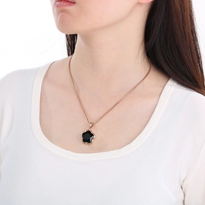 Close-up of rose gold snake chain with black five-petal flower pendant on woman neck